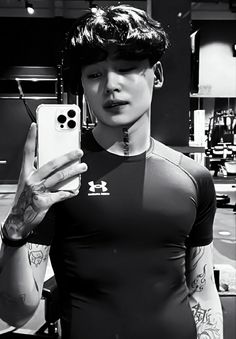 a man with tattoos taking a selfie in front of his cell phone while wearing a black shirt