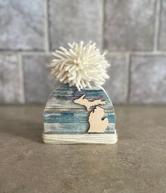 a small wooden hat with a white pom - pom on top of it