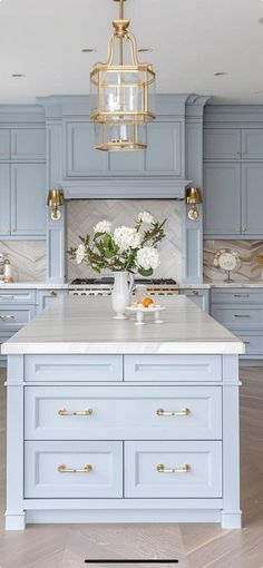 a kitchen with blue cabinets and white counter tops, gold hardware on the handles and pulls