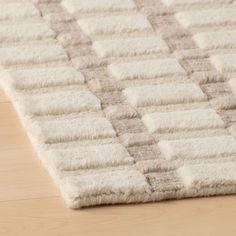 a close up of a rug on a wooden floor with white and gray colors,