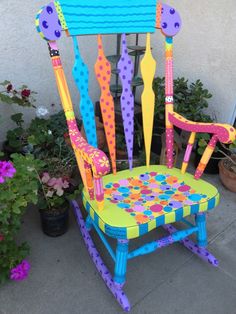 a brightly colored rocking chair sitting next to potted plants