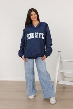 a woman standing in front of a white wall wearing a penn state sweatshirt