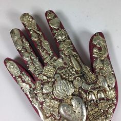 a hand that is covered in gold and silver jewelry on top of a white surface