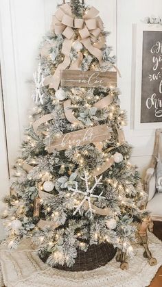 a decorated christmas tree in a living room with white and gold decorations on the top