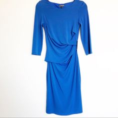 a blue dress hanging on a white wall with the back turned to show it's long sleeves