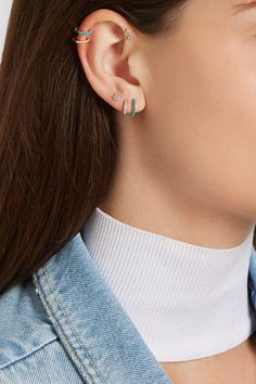 a woman wearing ear piercings and a denim jacket