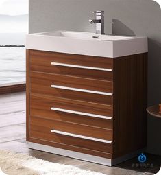 a bathroom vanity with drawers and a sink in front of a large body of water