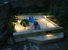 a little boy playing in the sand with his toy car and lights at night time