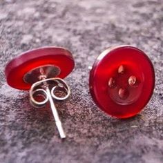 two red buttons sitting next to each other on top of a gray surface with silver pins