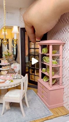 a doll house dining room with pink furniture and gold accessories on the table, as well as a miniature kitchen