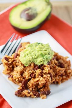 a white plate topped with rice covered in guacamole next to an avocado