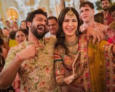 two people standing next to each other in front of a group of people wearing costumes