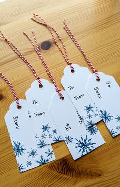 four tags with red and white twine on them sitting on a wooden table next to candy canes