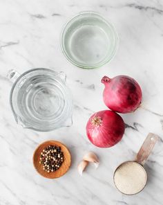 onions, garlic and seasoning on a marble counter top next to a measuring cup