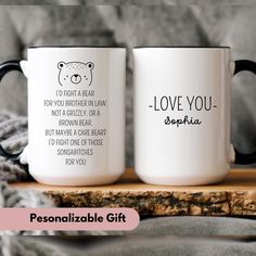 two personalized coffee mugs sitting on top of a wooden table next to a blanket