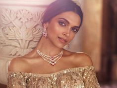 a woman in gold dress posing with her arms crossed and wearing jewelry on her chest