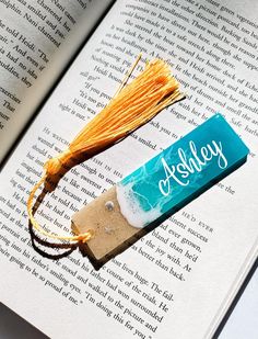 an open book with a piece of paper on top of it next to a tassel