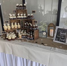 a table topped with lots of cupcakes next to a window