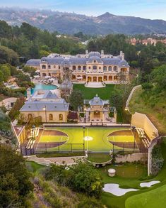 an aerial view of a large mansion with a green golf course in the foreground