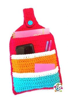 a crocheted bag with a cell phone in it and some pens and pencils