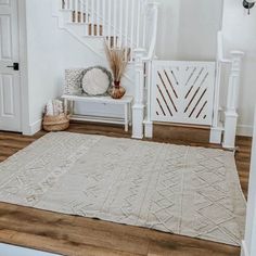 a living room with white walls and wooden floors, rugs on the floor and stairs