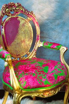 a pink and green chair sitting on top of a white fur covered floor next to a blue wall