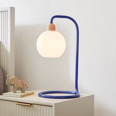 a blue lamp sitting on top of a white table next to a wooden elephant figurine