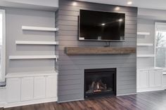 a flat screen tv mounted on the wall above a fireplace in a living room with hardwood floors