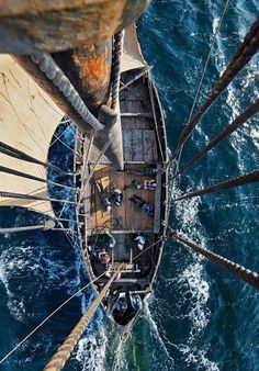 an overhead view of a sailboat in the ocean with people on it's deck