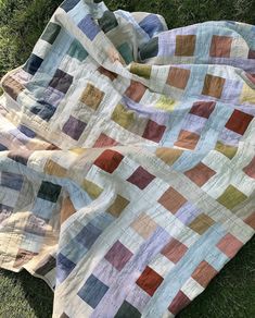 a patchwork quilt laying on the grass with it's back facing the camera