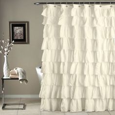 a white shower curtain with ruffles on it in a bathroom next to a toilet