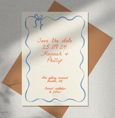 an orange and blue wedding save the date card on top of some brown envelopes