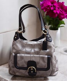 This Coach Campbell Hobo bag combines elegance and functionality with its khaki jacquard monogram design and mahogany leather trim. The interior features a dark brown sateen lining that's clean with no rips or stains, offering one zip pocket, two slip pockets, and three compartments--two outer compartments with snap closures and a center compartment with a zipper. The gold-tone hardware and classic hangtag add a touch of luxury. The straps are in good condition, and overall, the bag is in very g Elegant Brown Bag With Gunmetal Hardware, Elegant Brown Bags With Gunmetal Hardware, Hobo Shoulder Bag, Preppy Casual, Monogram Design, Leather Trim, Hobo Bag, Leather Trims, Purses And Handbags