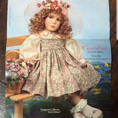 a doll sitting on top of a wooden bench wearing a dress and bonnet with flowers in her hair