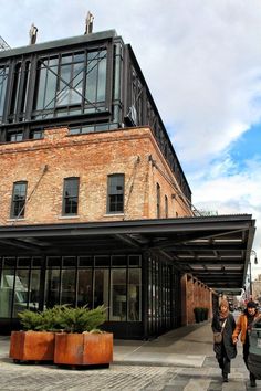 two people are walking down the sidewalk in front of a brick building with glass windows