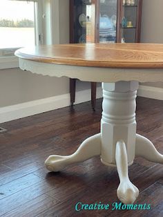 a dining room table with an oval wooden top and white legs on a hard wood floor