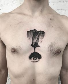 a man's chest with an eye and flower tattoo on it