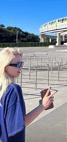 two women are standing in front of a train track and looking at their cell phones