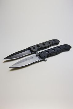 two black knives sitting next to each other on top of a white surface with holes in the blades