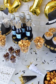 a table topped with lots of bottles of wine next to glasses filled with snacks and candies