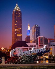 the cleveland sign is lit up at night in front of some tall buildings with lights on them