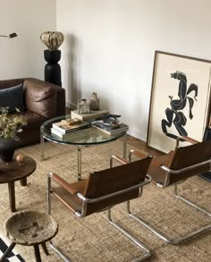 a living room filled with furniture and a painting on the wall next to a coffee table