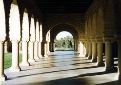 an arched walkway with columns and grass in the background