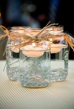 three mason jars filled with candles on top of a table