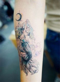 a woman's arm with a tattoo on it that has a mermaid sitting on top of a fish