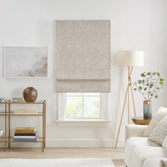 a living room filled with furniture and a large window covered in white roman blind shades