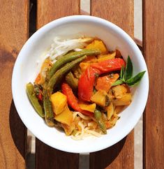 a white bowl filled with vegetables on top of a wooden table