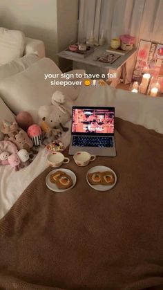 an open laptop computer sitting on top of a bed next to donuts and cupcakes