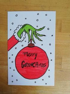 a christmas card with an image of a green hand holding a red ornament