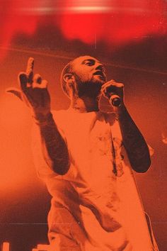 a man standing on top of a stage with his hands in the air and holding a microphone